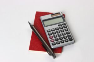 Calculator, notebook, and books representing Bible verses about money management and financial stewardship